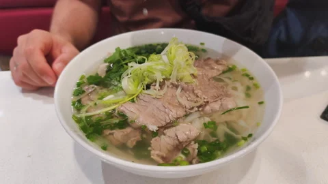 Vietnamese pho bo with beef and herbs is hot and tasty. Vietnamese pho bo is Stock Footage 325073669