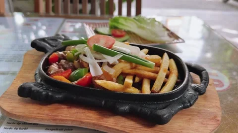 Vietnamese Sizzling Beef Bo Ne with French Fries in Cast iron cow-shaped frying Stock Footage 341542573