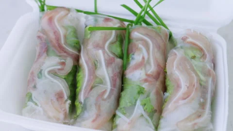 Vietnamese spring rolls with pork ear rotating in takeout box Stock Footage 337360235