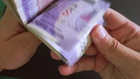 View of 100 indian rupee (INR) banknotes stack. Man's hands counting money. Stock Footage 296844055