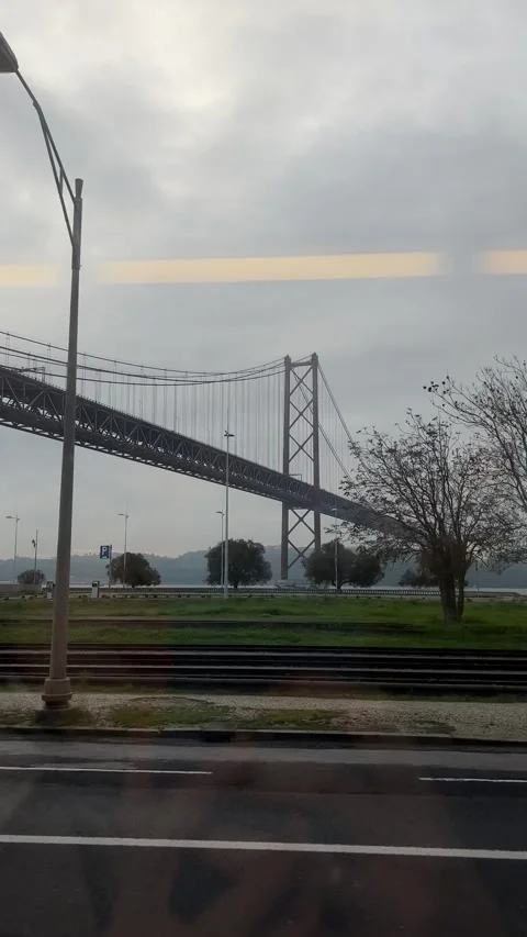 View of 25 de Abril Bridge from train window in Lisbon, Portugal. Vertical Stock Footage 241023723