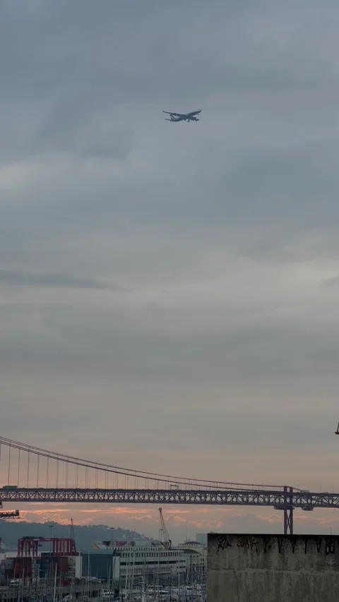 View of 25th April Bridge and airplane flying over in Lisbon. Vertical Stock Footage 241023713