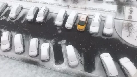 View from abofe snow falling on rows of cars in parking space in winter Stock Footage 279855821