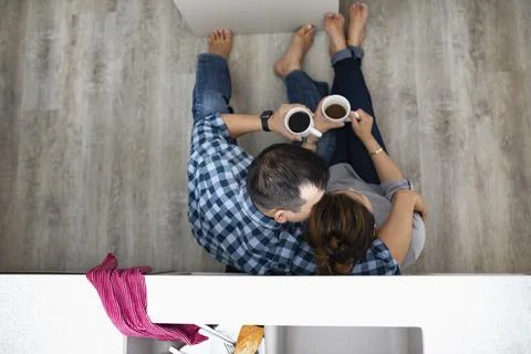 View from above affectionate couple drinking coffee on kitchen floor below sink Fotos Stock