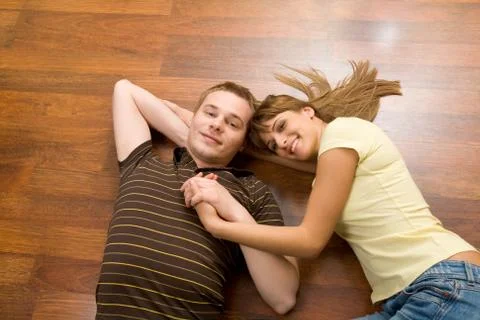 View from above of affectionate couple lying on the floor and looking at camera Fotos Stock