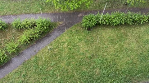 View from above from the balcony of a rainstorm on a path in a park  Vídeo Stock 336103657