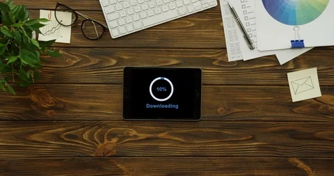 View from above on the black tablet device having a program downloading on its Stock Footage 95057463