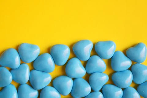 View from above. Blue dragee in the shape of hearts on a yellow background Foto stock