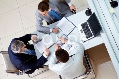 View from above of business men sitting at table in the office and discussing ne Stock Photos
