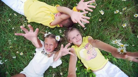 View from above, children lie on the grass, chamomile meadow, and stretch their Stock Footage