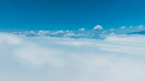View from above clouds showcases clear blue sky and fluffy white formations Stock Photos
