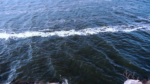 View from above on dark blue waves crashing against the rocky shore Stock-Footage 120868957