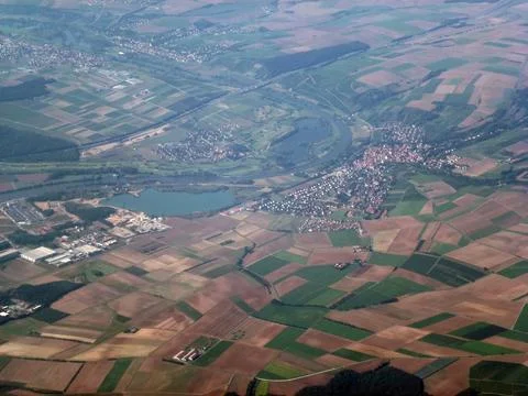 View from above of different colored fields, forests and small towns below Stock Photos