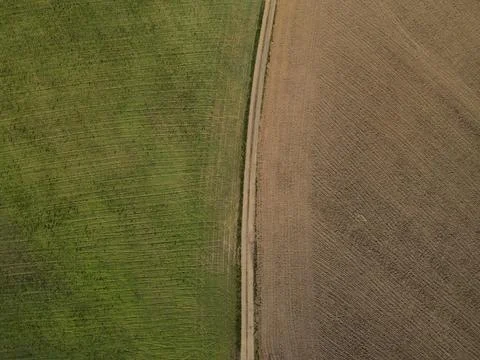 View from above of a dirt road between grass and plowed dirt Stock Photos