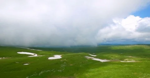 A view from above with a drone on the green grass covered with snow and snow pat Stock Footage 83756381
