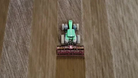 View from above. A farmer on a large tractor cultivates and plows the soil in Stock Footage 261267909
