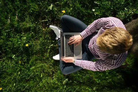 View from above , freelancer is sitting under a tree on a sunny day. working  Stock Photos