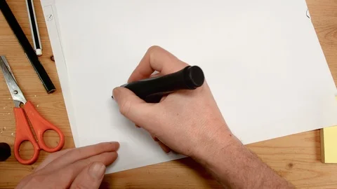 View from above, an interior architect's hand draws a house and written home on Stock Footage 104252422