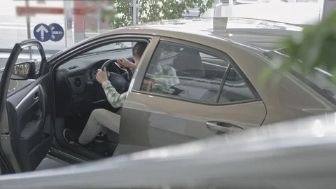 View from above of man sitting in car in auto salon Stock Footage 101113105