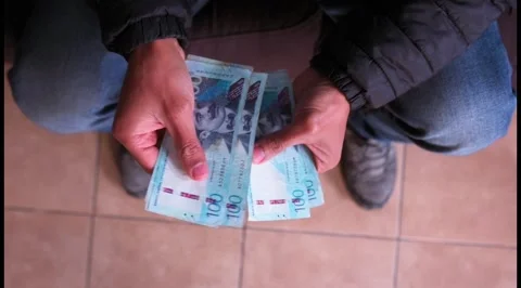 View from above of a man's hands counting 100 nuevos soles bills at home. Stock Footage 283686137