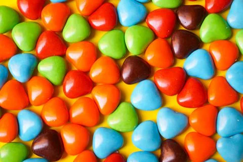 View from above on a multi-colored dragee in the shape of hearts. Stock Photos