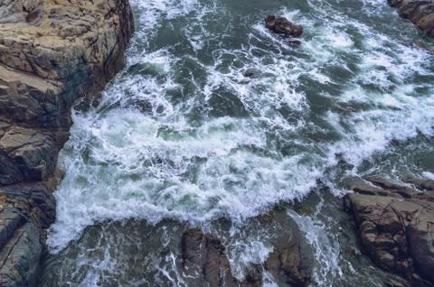 View from above on restless sea waves bumping intorugged stones Stock Photos