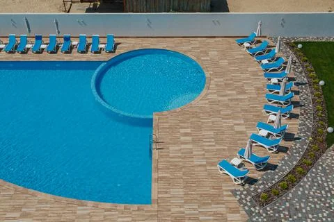 View from above on the round pool with blue water and sun loungers around Stock Photos