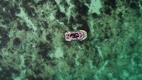 A view from above of small boat with two people, which sails through clear sea Stock Footage 233229114