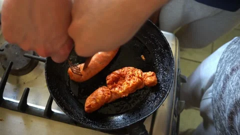 View from above trying to remove the plastic from a sausage by frying it in the Stock Footage 170015752
