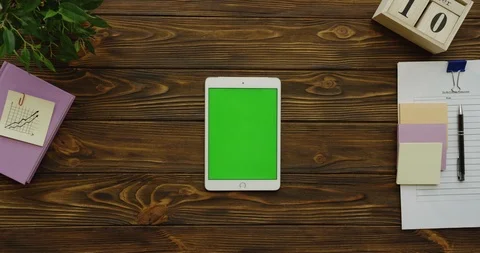 View above on the vertical white tablet device with a green screen on the wooden 스톡 동영상 88394567