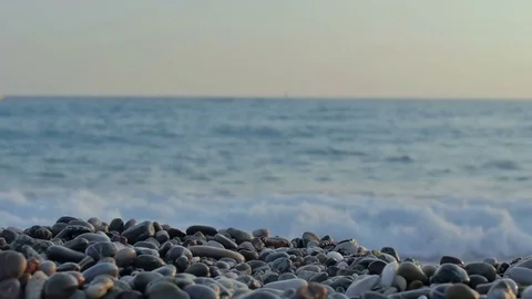 A view from above of waves, foam and colored stones. Pebble beach Stock Footage 81537485