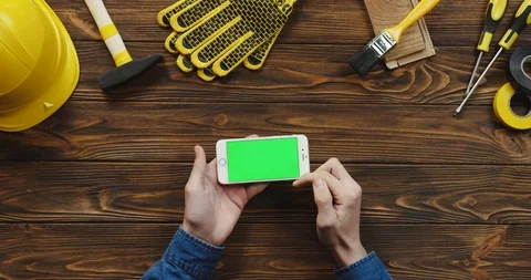 View from above on the white horizontal smartphone on the wooden desk of workman Stock Footage 96182722