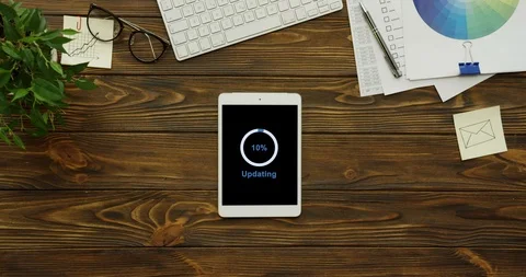 View from above on the white tablet device having a program updating on its Stock Footage 95102201