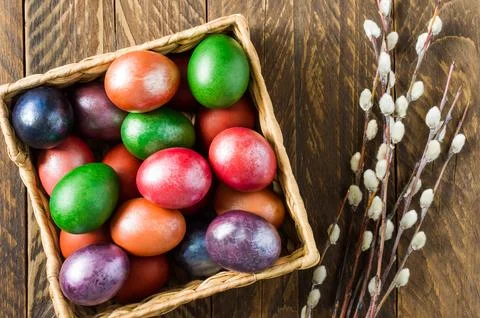 View from above of a wooden box with Easter colorful eggs and willow twigs... Stock Photos