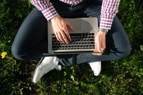View from above , young man freelancer is sitting under a tree on a sunny day Stock Photos
