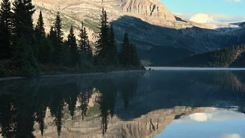 View across a calm mountain lake surrounded by dense evergreen trees in a Stock Footage 333074883