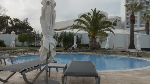 View across empty sun loungers, pool and palm trees Stock Footage 106499532