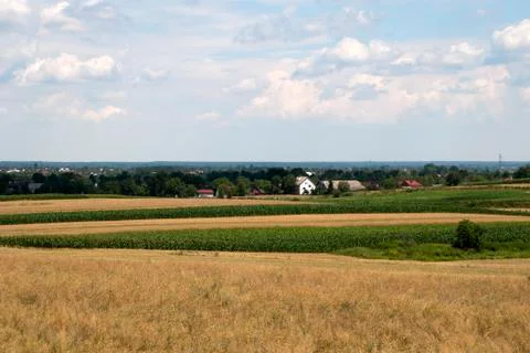 View across farm fields to distant village in summer Stock Photos