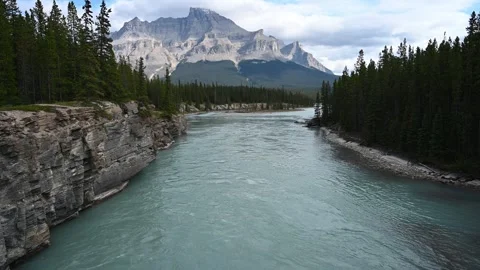 View across a large emerald green river flowing through a mountain cliffs with Stock Footage 333074886