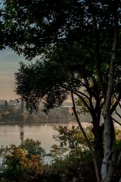 View across the river with trees framing the scene at dawn showing building.. Stock Photos