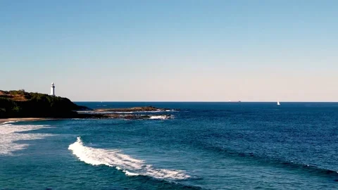 View across the rolling surf to a headland with a lighthouse Video stock 169207701