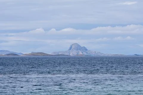 View across the sea towards an island with a distinctive mountain in Scandi.. Stock Photos
