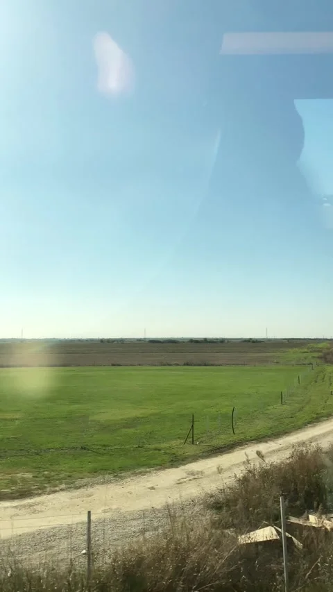 View of agricultural farmlands through moving train window on a sunny day. Stock Footage 298242501