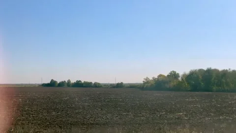 View of agricultural farmlands through moving train window on a sunny day Stock Footage 298242553