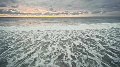 View from the air of the waves gently lapping the shore in the evening Stock Photos
