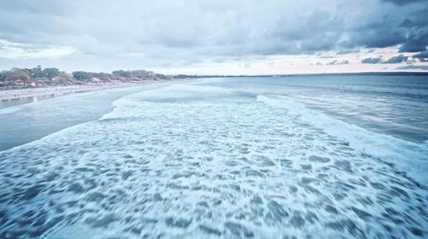 View from the air of the waves gently lapping the shore in the evening Stock Photos