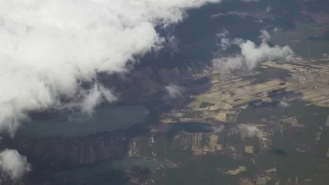 View from the airplane. Clouds and the earth's surface with forests, fields a Stock Footage 141528325