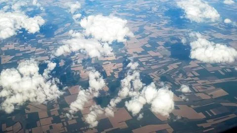 View from the airplane on clouds flying over fields Stock Photos
