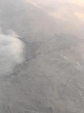 View from airplane at clouds, under clouds of mountains Stock Photos