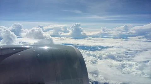 View of an airplane engine from a passenger window during flight above a layer o Stock Photos